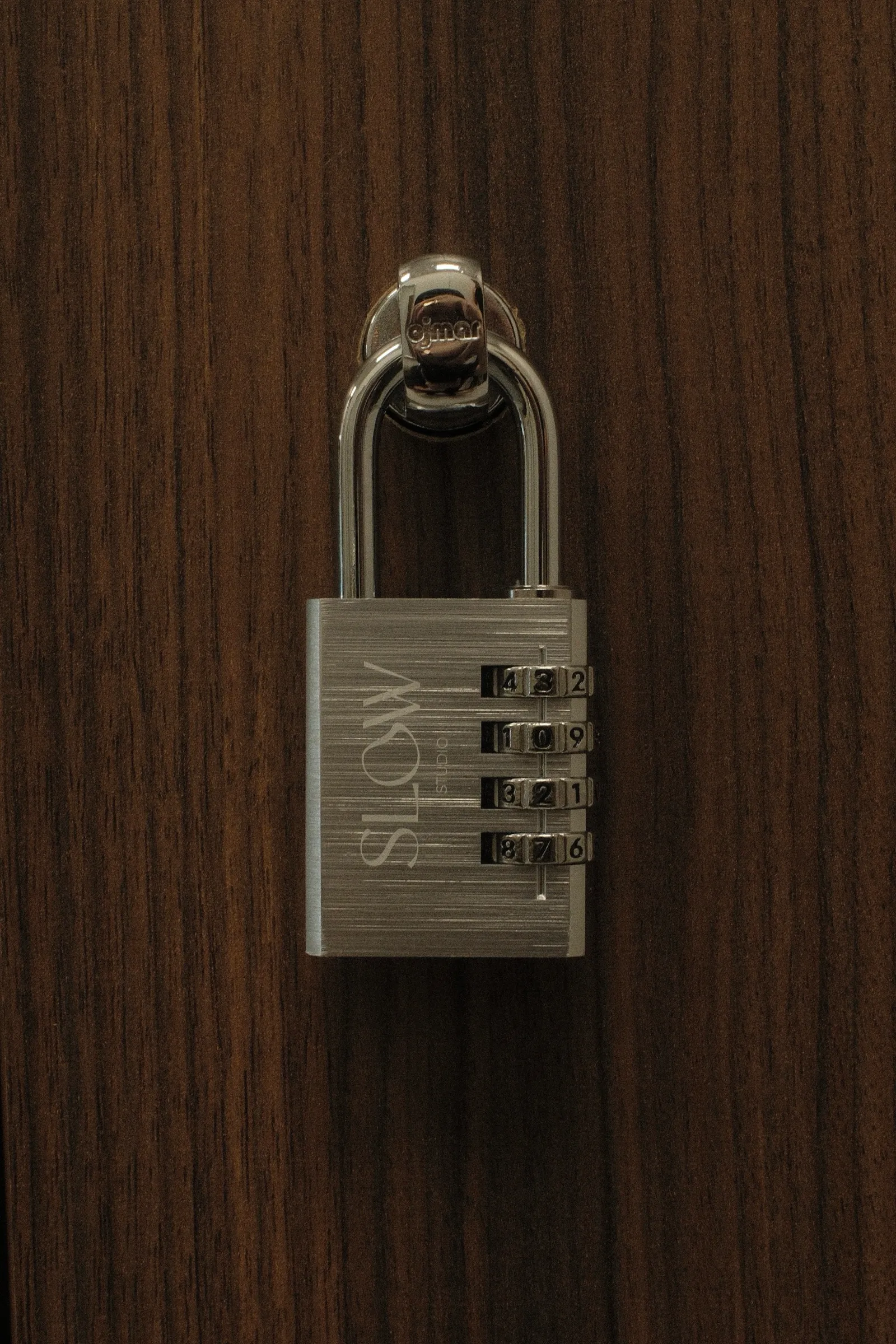 Cadenas à code gravé Slow Studio sur la porte d'un casier en noyer.