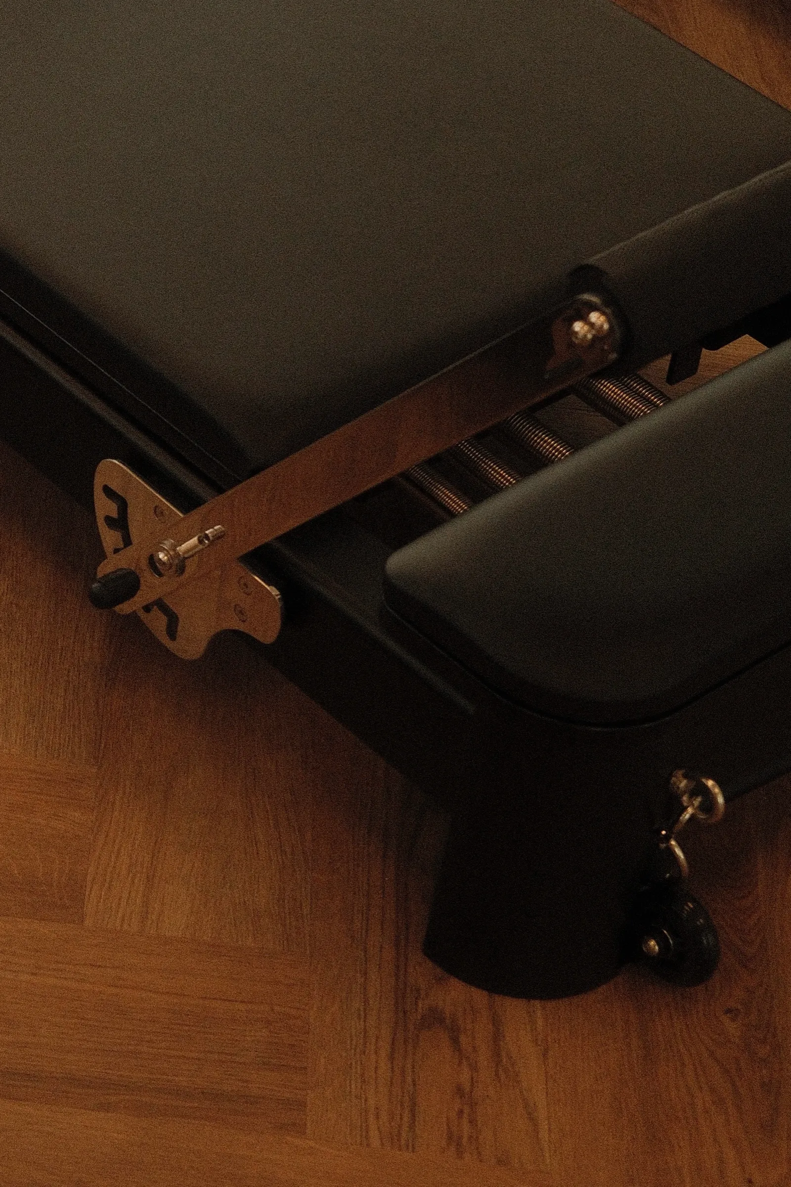 Détail du mécanisme à ressorts d'un Reformer sur le parquet à chevrons.