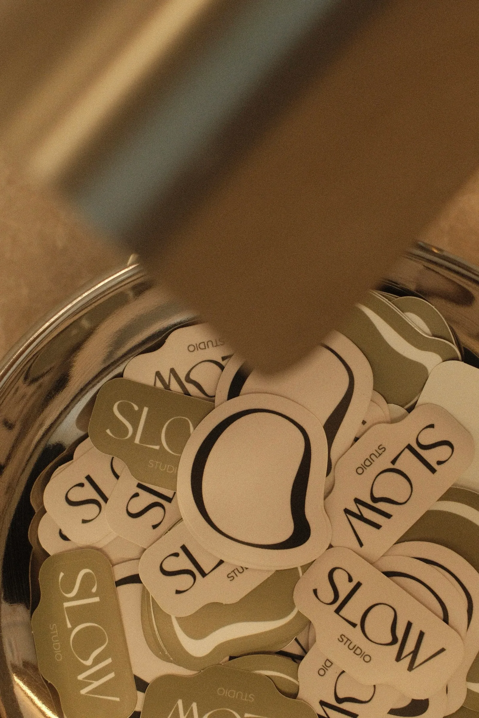 Des stickers Slow Studio crème et olive rassemblés dans un bocal en verre.